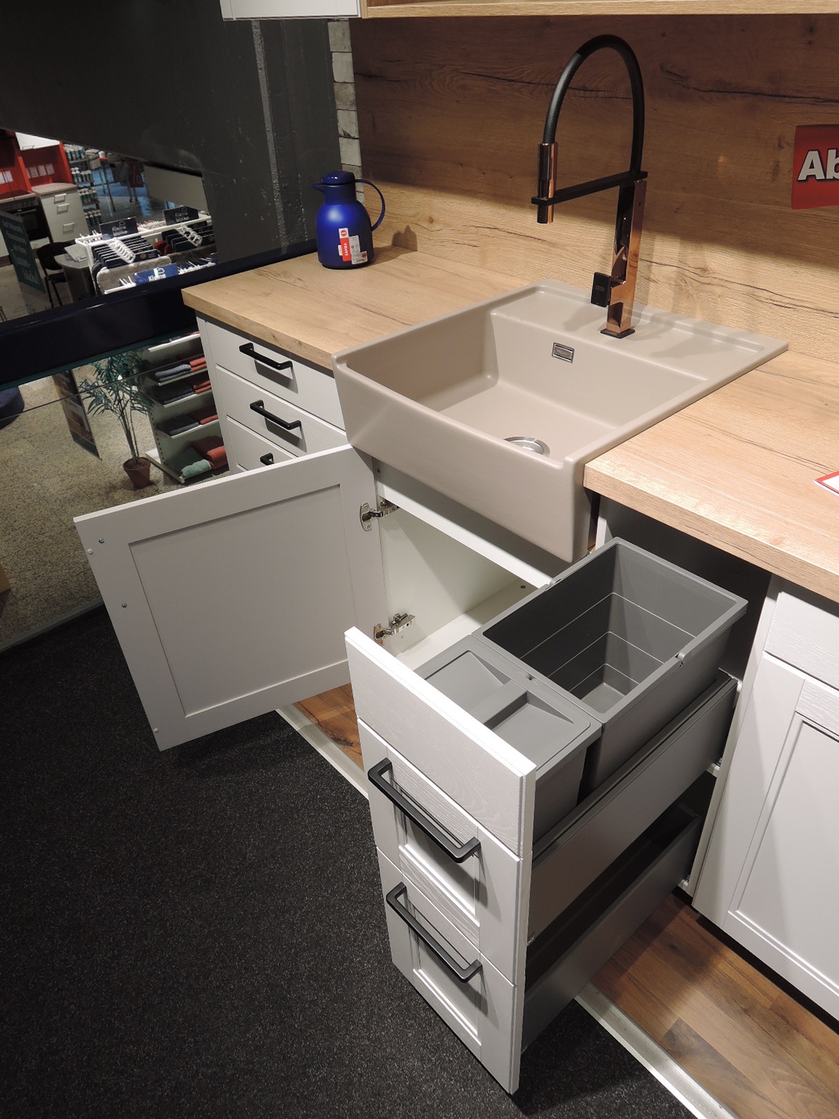 Blick in den geöffneten Spülenunterschrank sowie in das Müllsystem rechts vom Spülenunterschrank