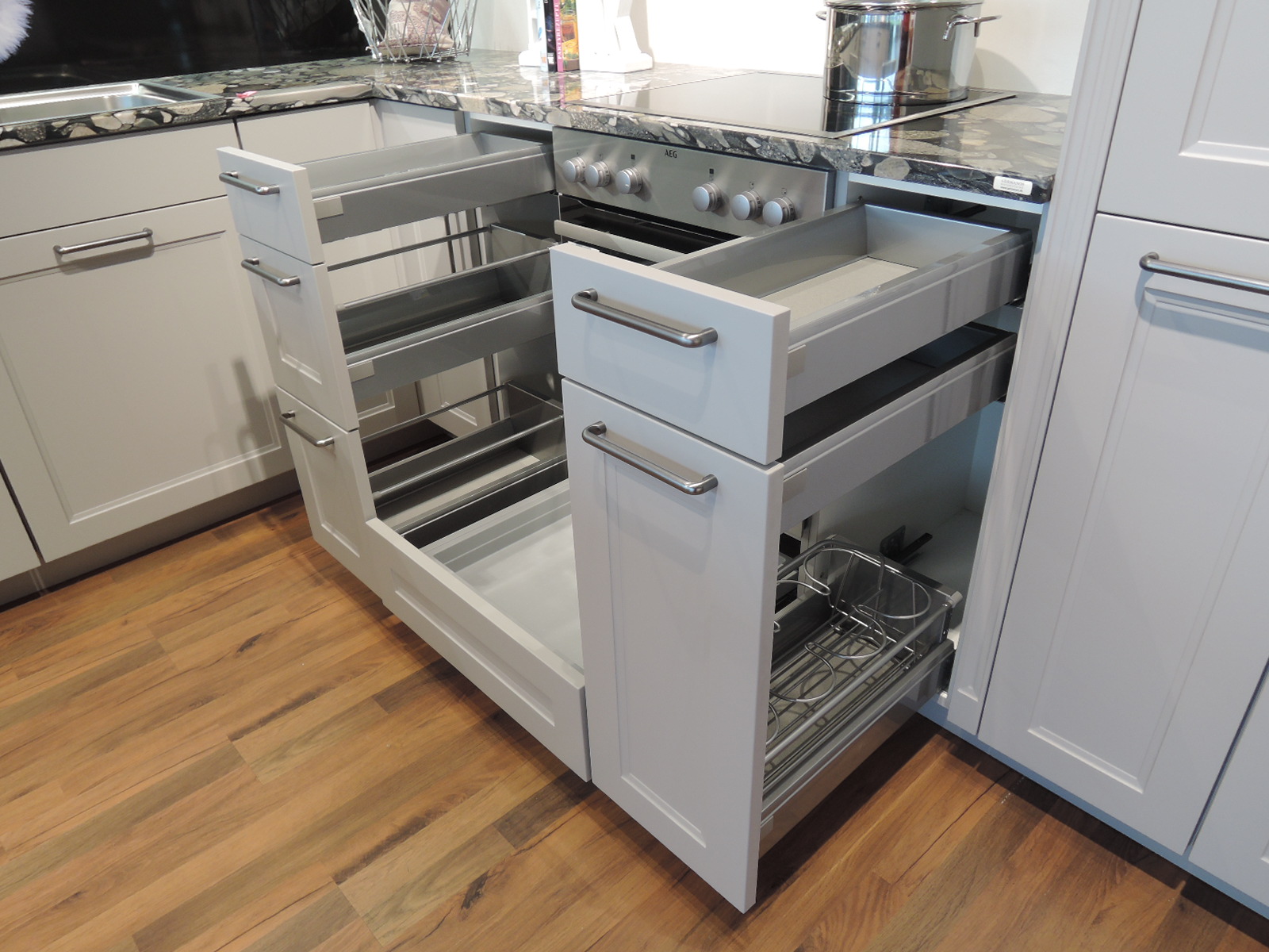 Blick in die geöffneten Schubladen und Auszüge links und rechts vom Einbauherd mit Schublade unterhalben vom Einbauherd